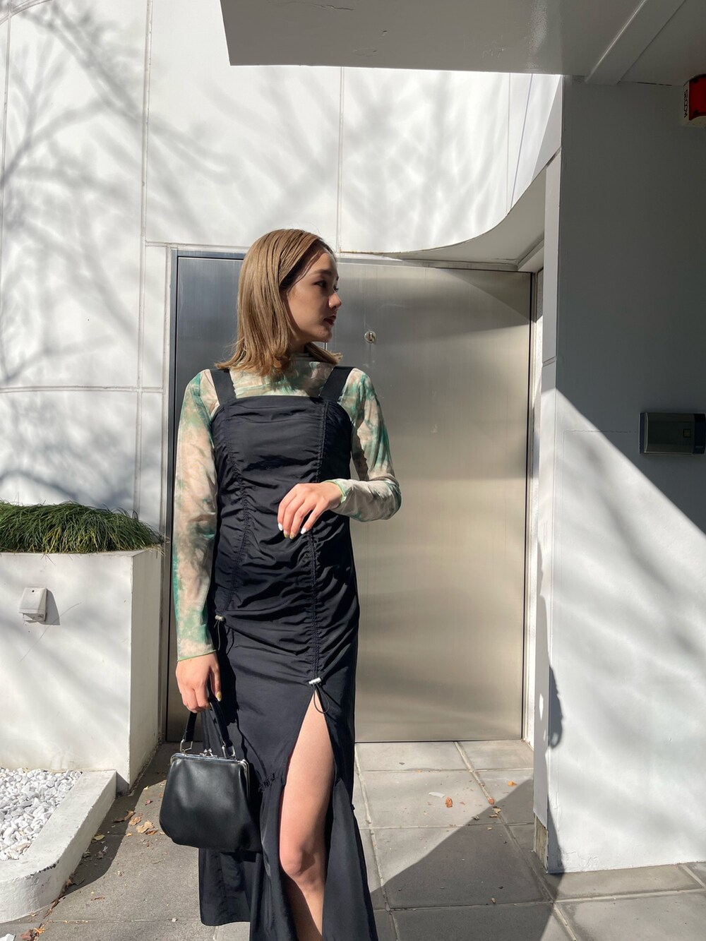 ブラック系のワンピース、ブラック系のショルダーバッグ、ブラック系のブーツを着用したレディースの冬コーディネートの5枚目の写真