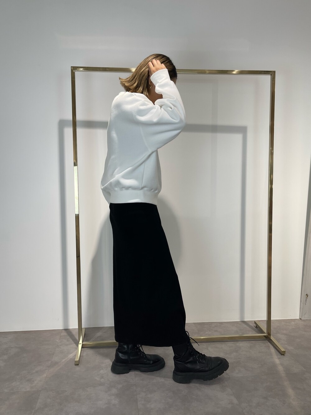 ブラック系のスカート、ブラック系のブーツ、ホワイト系のスウェットを着用したレディースの秋コーディネートの4枚目の写真