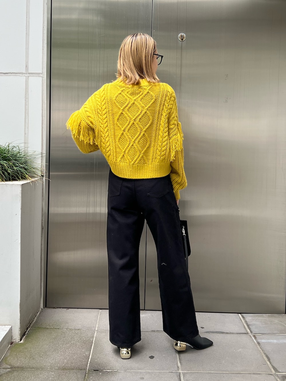 ブラック系のショルダーバッグ、イエロー系のニット/セーター、ブラック系のデニムパンツを着用したレディースの秋コーディネートの3枚目の写真