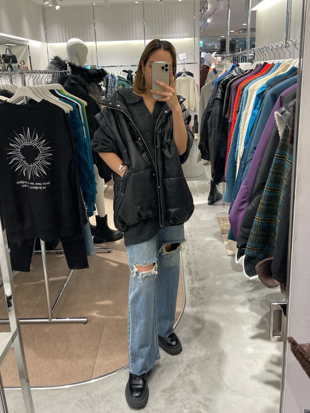 グレー系のニット/セーター、ブラック系のブーツ、ブルー系のデニムパンツを着用したレディースの秋コーディネートの7枚目の写真