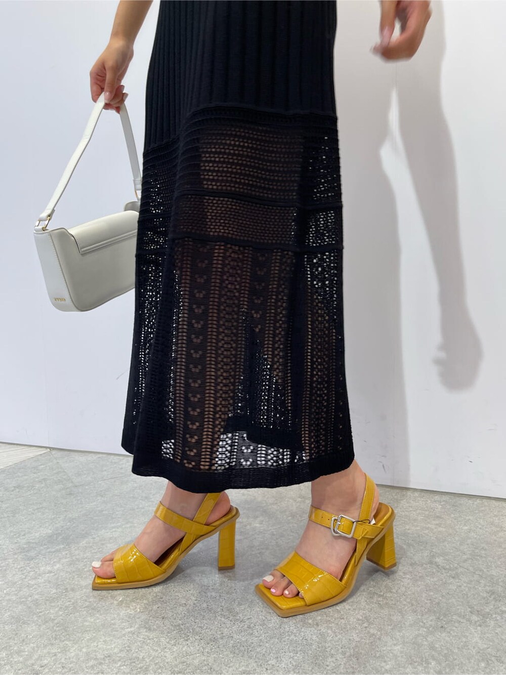 イエロー系のサンダル、ホワイト系のショルダーバッグ、ブラック系のスカートを着用したレディースの夏コーディネートの6枚目の写真