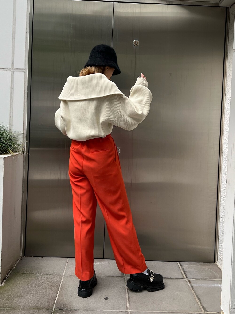 オレンジ系のスラックス、ホワイト系のニット/セーター、ブラック系のローファーを着用したレディースの秋コーディネートの2枚目の写真