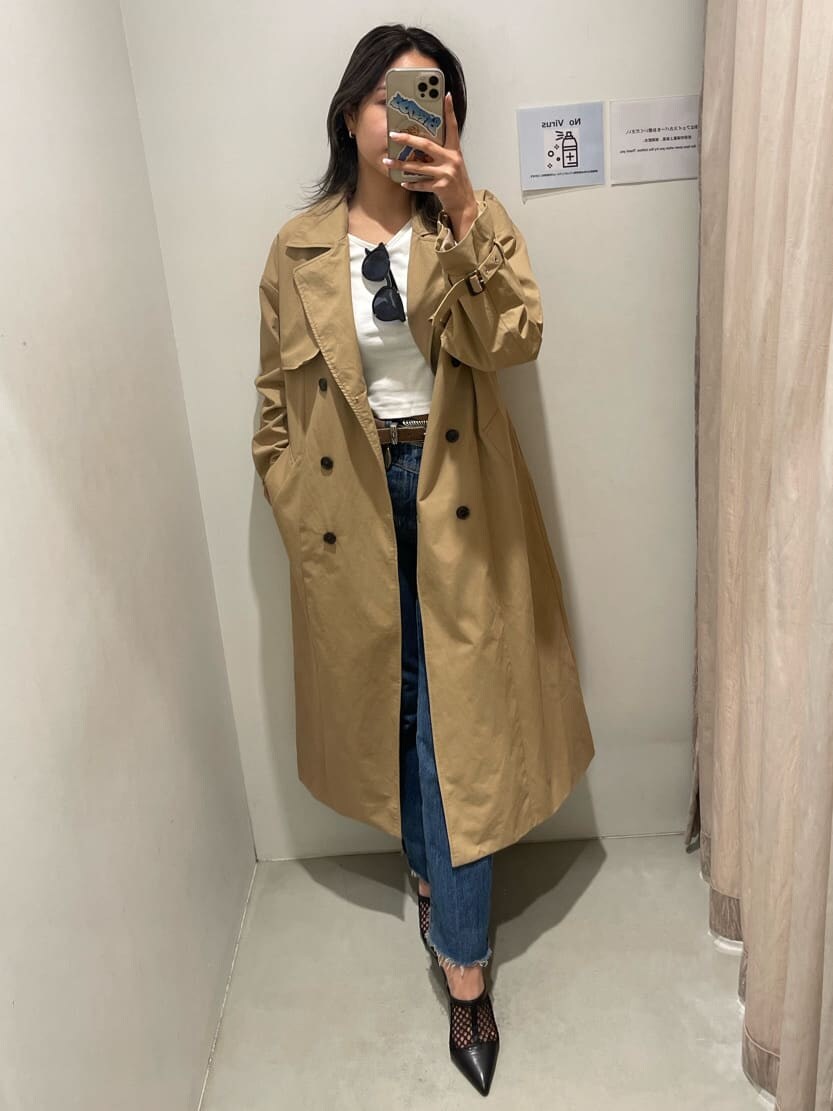 ブラック系のパンプス、ベージュ系のトレンチコート、ブルー系のデニムパンツを着用したレディースの冬コーディネートの2枚目の写真