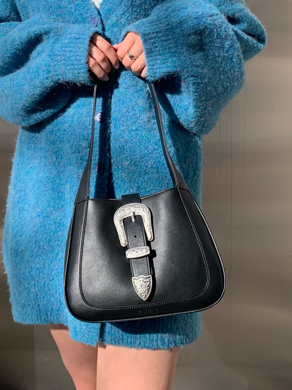 ブラック系のハンドバッグ、ブルー系のカーディガン/ボレロ、ホワイト系のTシャツ/カットソーを着用したレディースの冬コーディネートの8枚目の写真