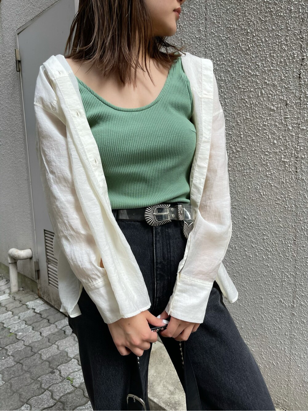 ブラック系のデニムパンツ、ホワイト系のシャツ/ブラウス、グリーン系のタンクトップを着用したレディースの春コーディネートの5枚目の写真