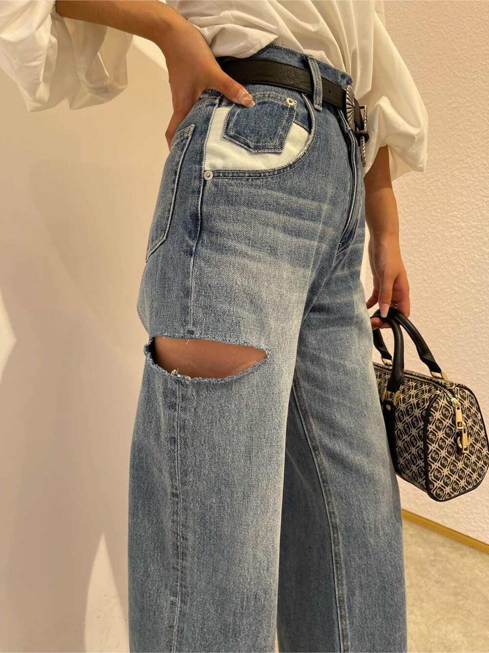 ブラック系のサンダル、ブラック系のボストンバッグ、ブルー系のデニムパンツを着用したレディースの夏コーディネートの6枚目の写真