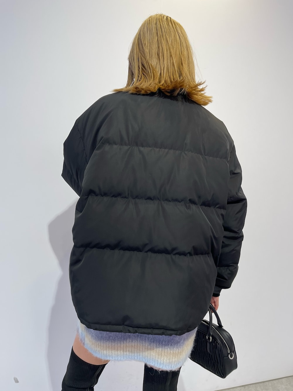 パープル系のニット/セーター、ブラック系のブーツ、ブラック系のダウンジャケット/コートを着用したレディースの冬コーディネートの7枚目の写真