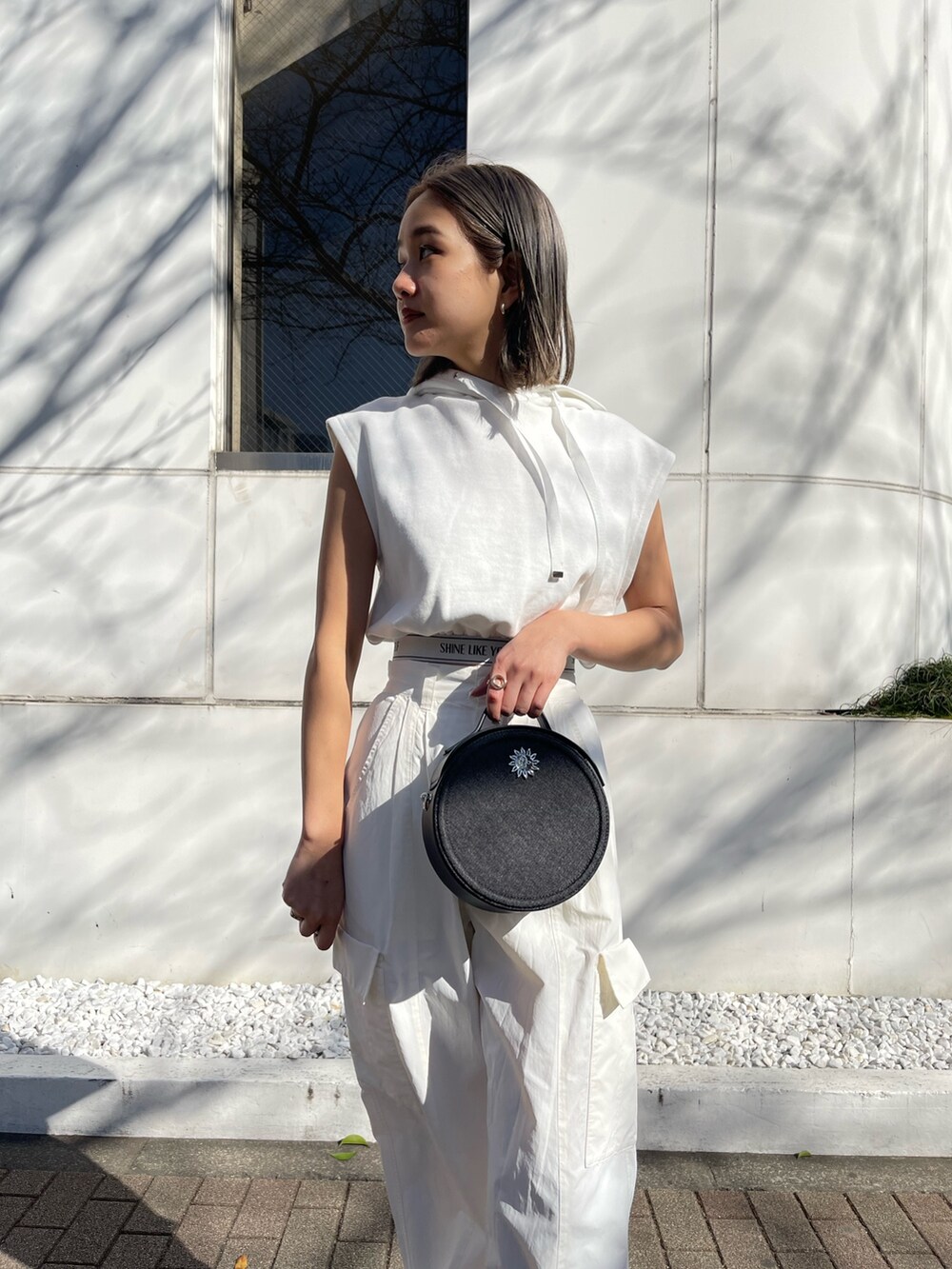 ホワイト系のブーツ、ホワイト系のカーゴパンツ、ブラック系のショルダーバッグを着用したレディースの春コーディネートの4枚目の写真