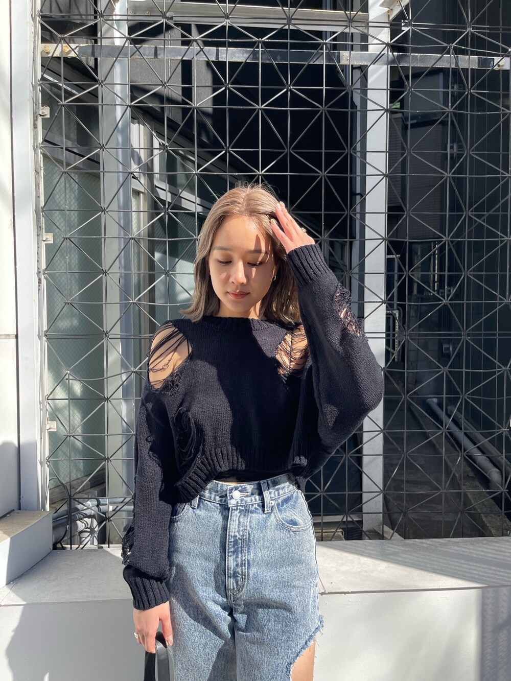 ブラック系のニット/セーター、ブラック系のブーツ、ブラック系のハンドバッグを着用したレディースの春コーディネートの4枚目の写真