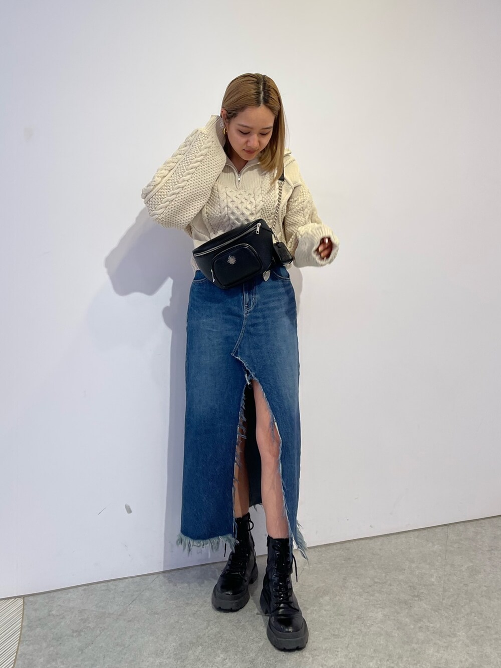 ブルー系のデニムスカート、ブラック系のブーツ、ホワイト系のニット/セーターを着用したレディースの冬コーディネートの2枚目の写真