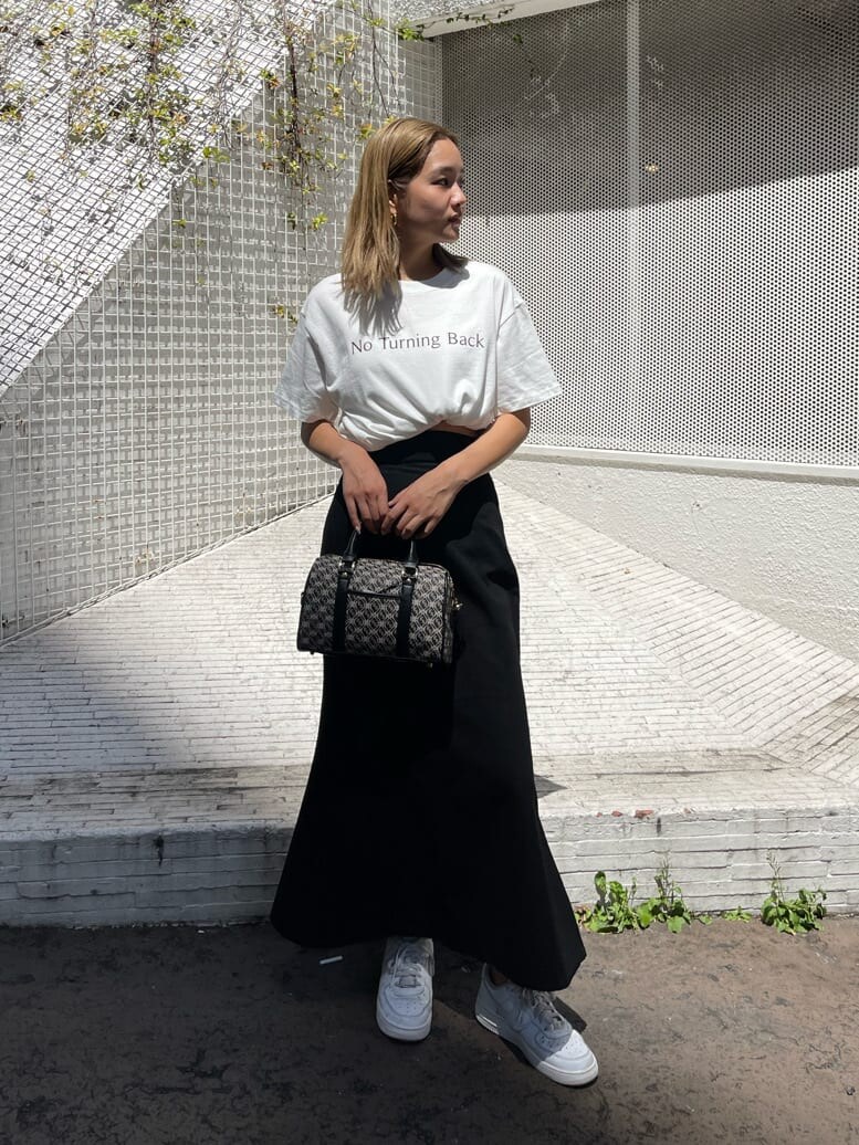 ブラック系のスカート、ブラック系のボストンバッグ、ホワイト系のTシャツ/カットソーを着用したレディースの夏コーディネートの2枚目の写真
