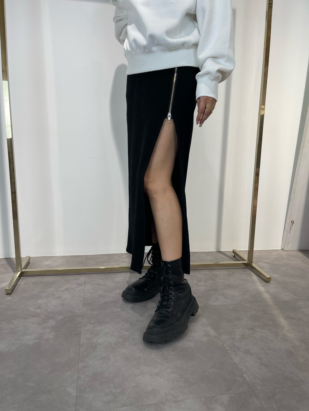 ブラック系のスカート、ブラック系のブーツ、ホワイト系のスウェットを着用したレディースの秋コーディネートの6枚目の写真