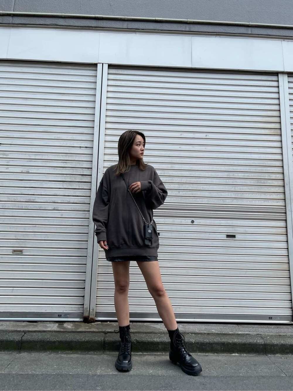 ブラック系のスカート、ブラック系のスウェット、ブラック系のブーツを着用したレディースの夏コーディネートの2枚目の写真