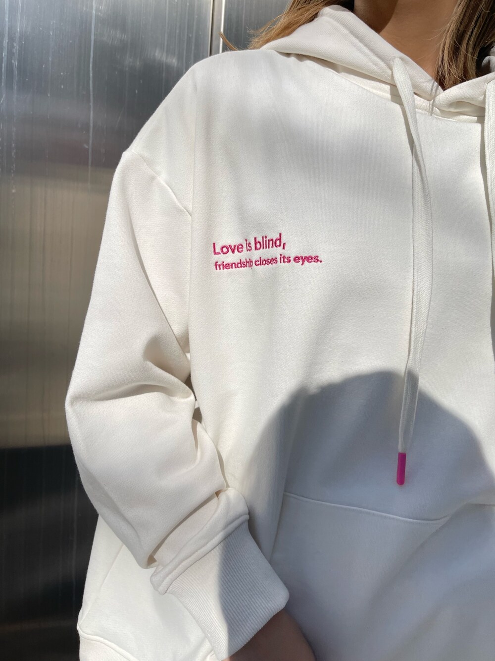 ホワイト系のパーカー、ホワイト系のショルダーバッグ、ブラック系のブーツを着用したレディースの冬コーディネートの6枚目の写真