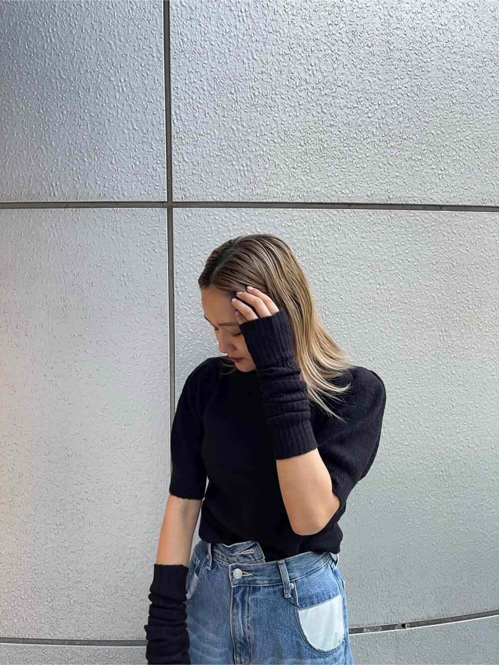 ブラック系のブーツ、ブラック系のニット/セーター、ブルー系のデニムパンツを着用したレディースの秋コーディネートの5枚目の写真