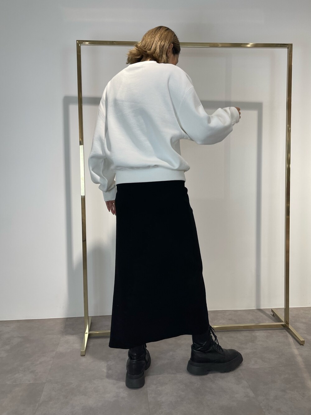 ブラック系のスカート、ブラック系のブーツ、ホワイト系のスウェットを着用したレディースの秋コーディネートの3枚目の写真