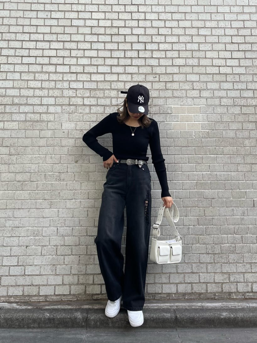 ブラック系のデニムパンツ、ブラック系のニット/セーター、ホワイト系のショルダーバッグを着用したレディースの冬コーディネートの4枚目の写真