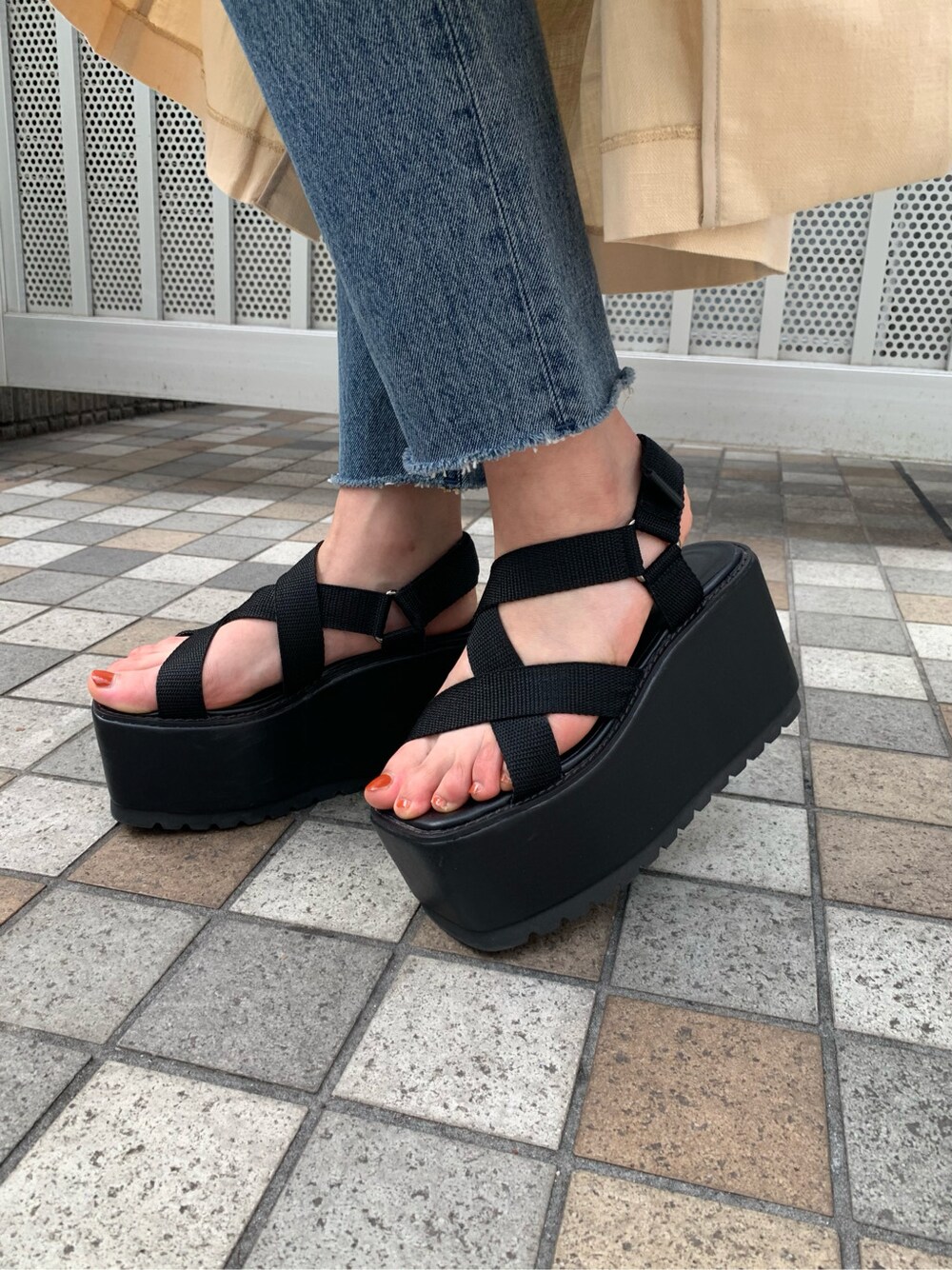 ブルー系のデニムパンツ、ブラック系のサンダル、ベージュ系のチェスターコートを着用したレディースの春コーディネートの8枚目の写真