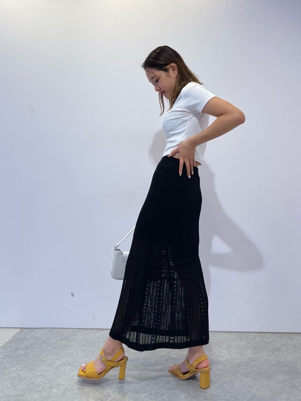 イエロー系のサンダル、ホワイト系のショルダーバッグ、ブラック系のスカートを着用したレディースの夏コーディネートの3枚目の写真