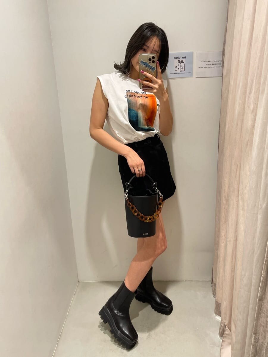 ブラック系のスカート、ホワイト系のTシャツ/カットソー、ブラック系のブーツを着用したレディースの春コーディネートの3枚目の写真