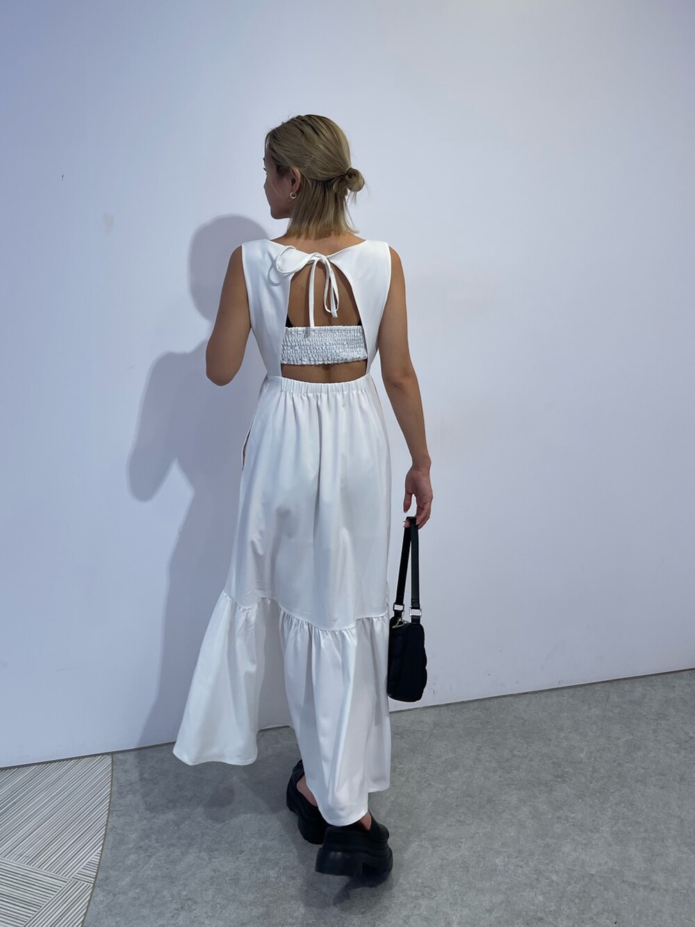 ホワイト系のワンピース、ブラック系のハンドバッグ、ブラック系のサンダルを着用したレディースの夏コーディネートの4枚目の写真