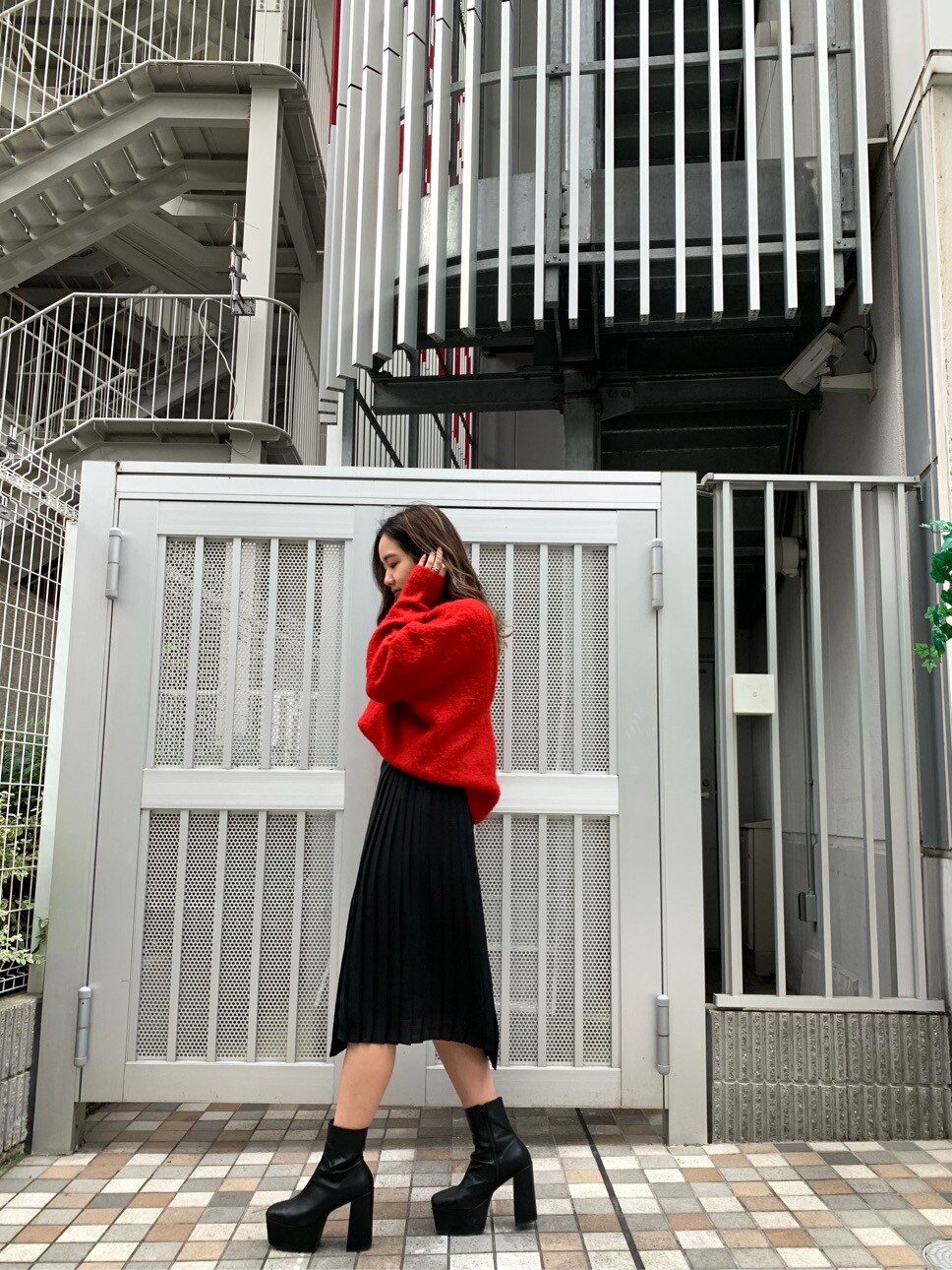 レッド系のニット/セーター、ブラック系のスカートを着用したレディースの秋コーディネートの2枚目の写真