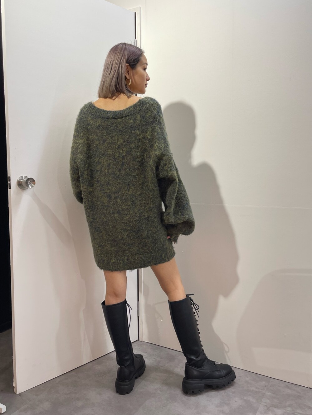 グリーン系のカーディガン/ボレロ、ブラック系のブーツ、ゴールド系のピアス（両耳用）を着用したレディースの秋コーディネートの3枚目の写真