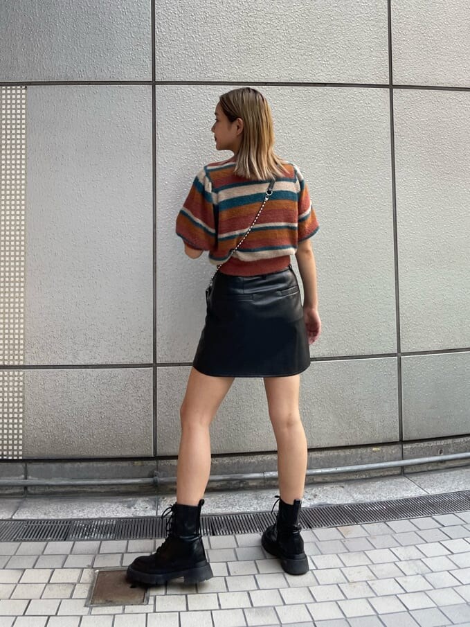 ブラック系のブーツ、ブラック系のショルダーバッグ、ブラック系のスカートを着用したレディースの秋コーディネートの3枚目の写真