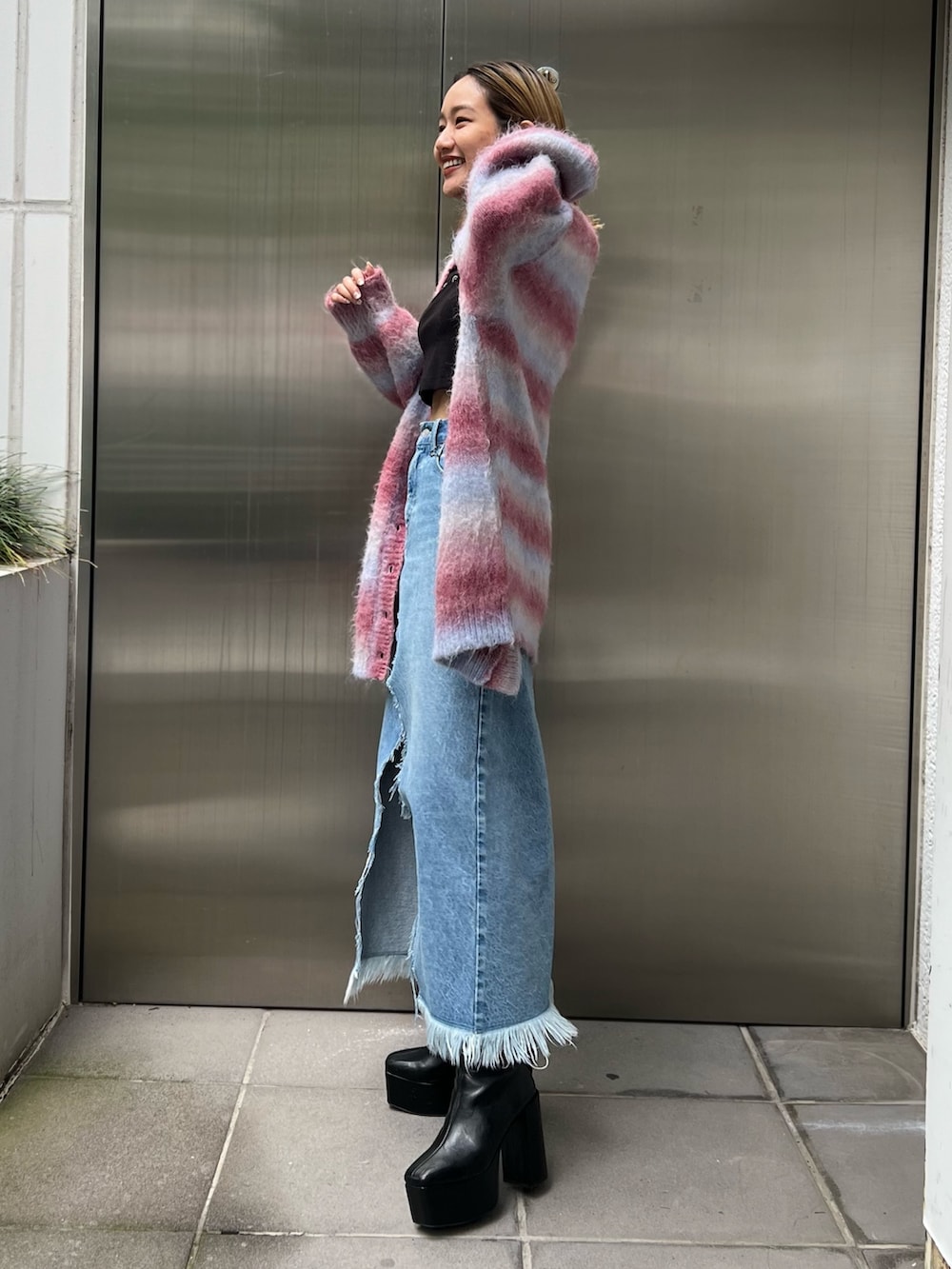 ブラック系のTシャツ/カットソー、ブルー系のデニムスカート、ピンク系のカーディガン/ボレロを着用したレディースの秋コーディネートの2枚目の写真