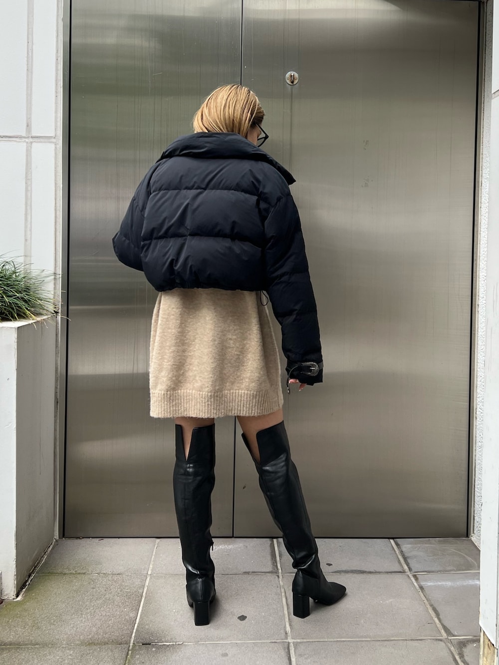 ベージュ系のワンピース、ブラック系のダウンジャケット/コート、ブラック系のブーツを着用したレディースの秋コーディネートの3枚目の写真