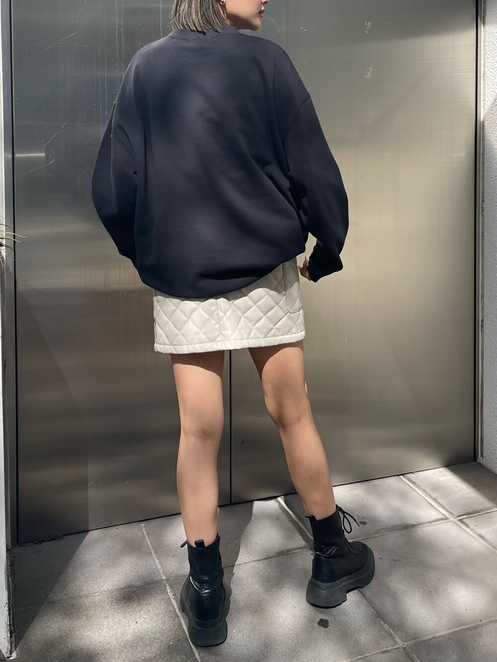 ブラック系のスウェット、ホワイト系のスカート、ブラック系のブーツを着用したレディースの秋コーディネートの3枚目の写真