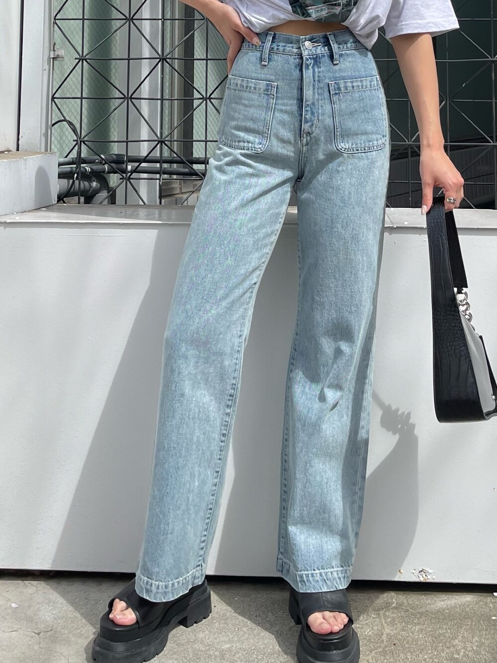 グレー系のTシャツ/カットソー、ブルー系のデニムパンツ、ブラック系のサンダルを着用したレディースの春コーディネートの6枚目の写真