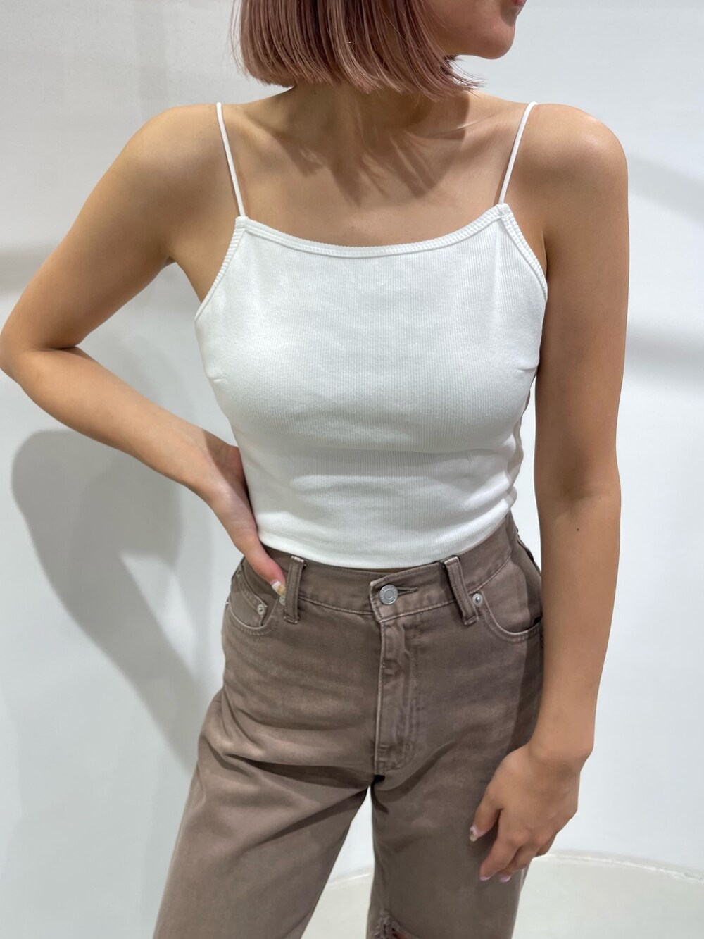 ブラック系のサンダル、ブラウン系のデニムパンツ、ホワイト系のキャミソールを着用したレディースの夏コーディネートの7枚目の写真