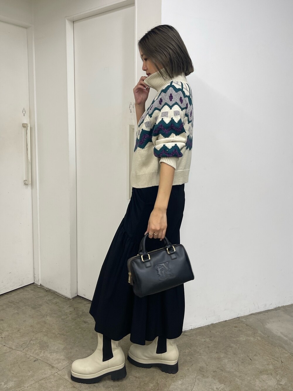 ブラック系のスカート、ホワイト系のブーツ、ホワイト系のニット/セーターを着用したレディースの秋コーディネートの2枚目の写真