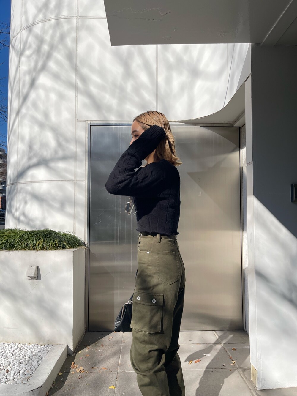 ブラック系のショルダーバッグ、ブラック系のカーディガン/ボレロ、ホワイト系のブーツを着用したレディースの冬コーディネートの4枚目の写真