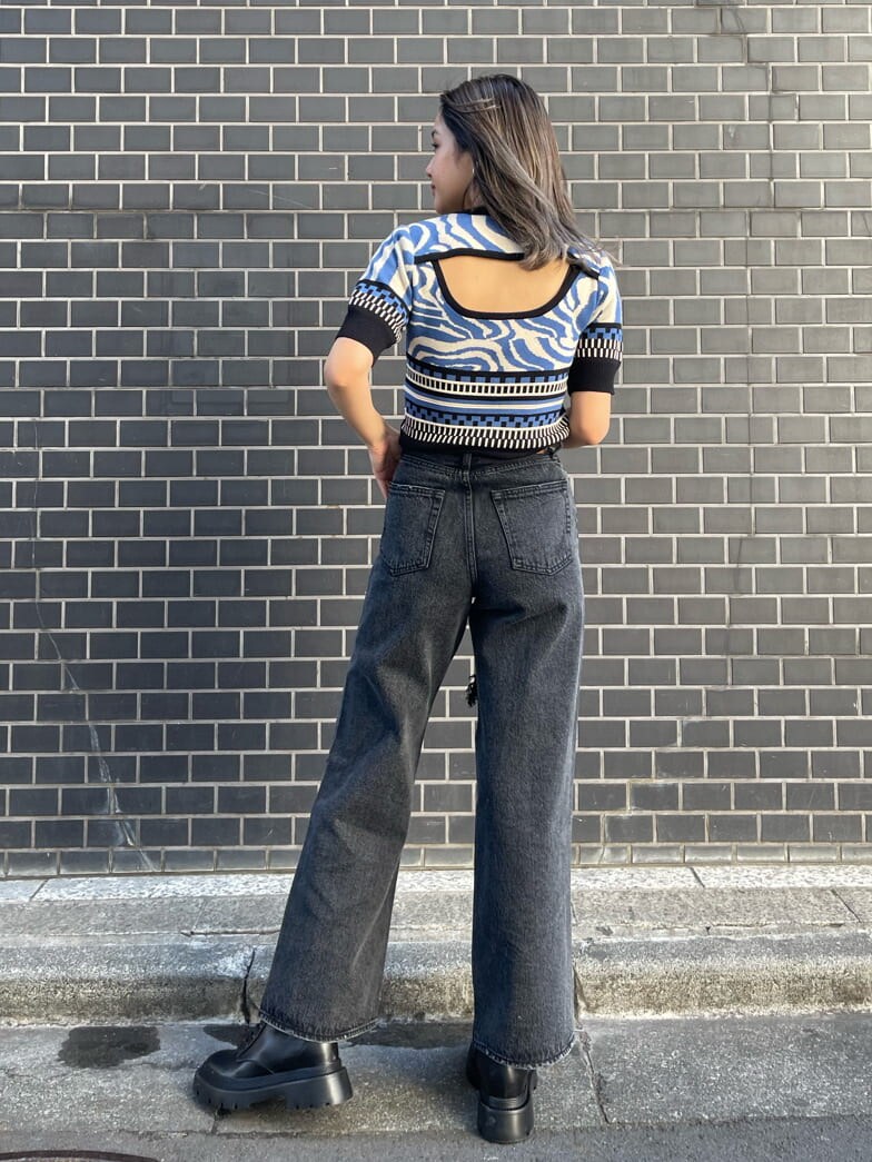 ブラック系のデニムパンツ、ブルー系のニット/セーター、ブラック系のブーツを着用したレディースの春コーディネートの3枚目の写真