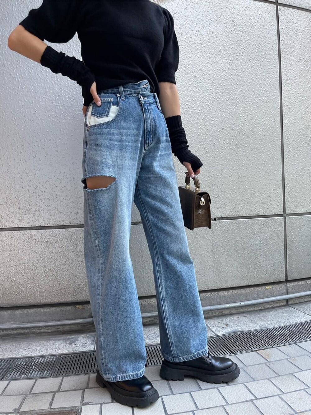 ブラック系のブーツ、ブラック系のニット/セーター、ブルー系のデニムパンツを着用したレディースの秋コーディネートの6枚目の写真