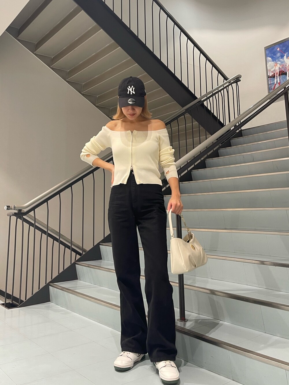 ホワイト系のニット/セーター、ブラック系のデニムパンツ、ホワイト系のハンドバッグを着用したレディースの夏コーディネートの2枚目の写真