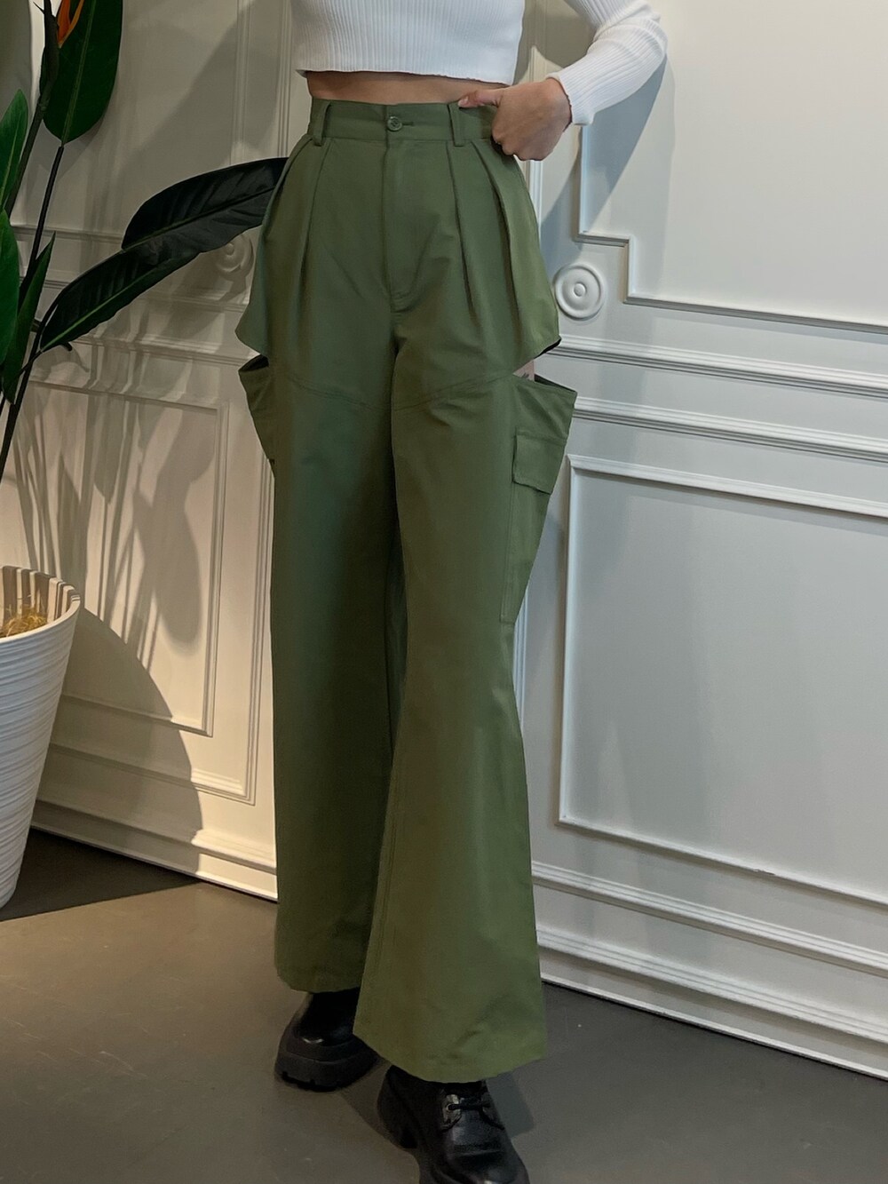 グリーン系のニット/セーター、ブラック系のブーツ、ベージュ系のカーゴパンツを着用したレディースの春コーディネートの2枚目の写真