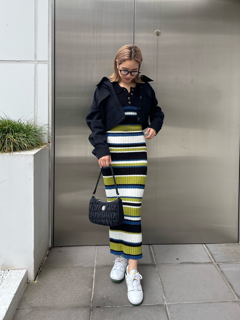 ブラック系のワンピース、ブラック系のミリタリージャケット、ブラック系のハンドバッグを着用したレディースの春コーディネートの3枚目の写真