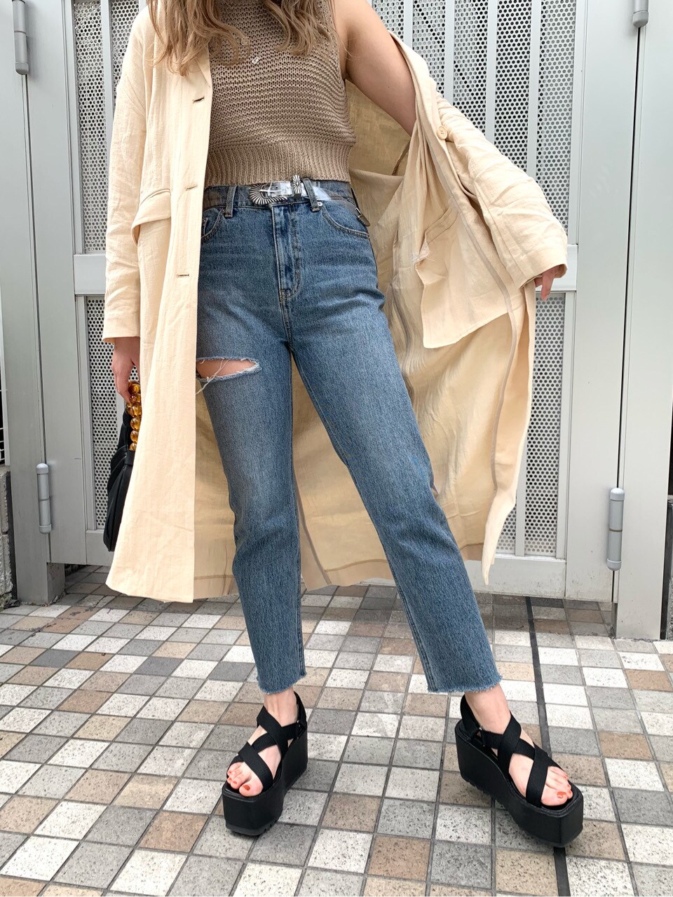 ブルー系のデニムパンツ、ブラック系のサンダル、ベージュ系のチェスターコートを着用したレディースの春コーディネートの10枚目の写真