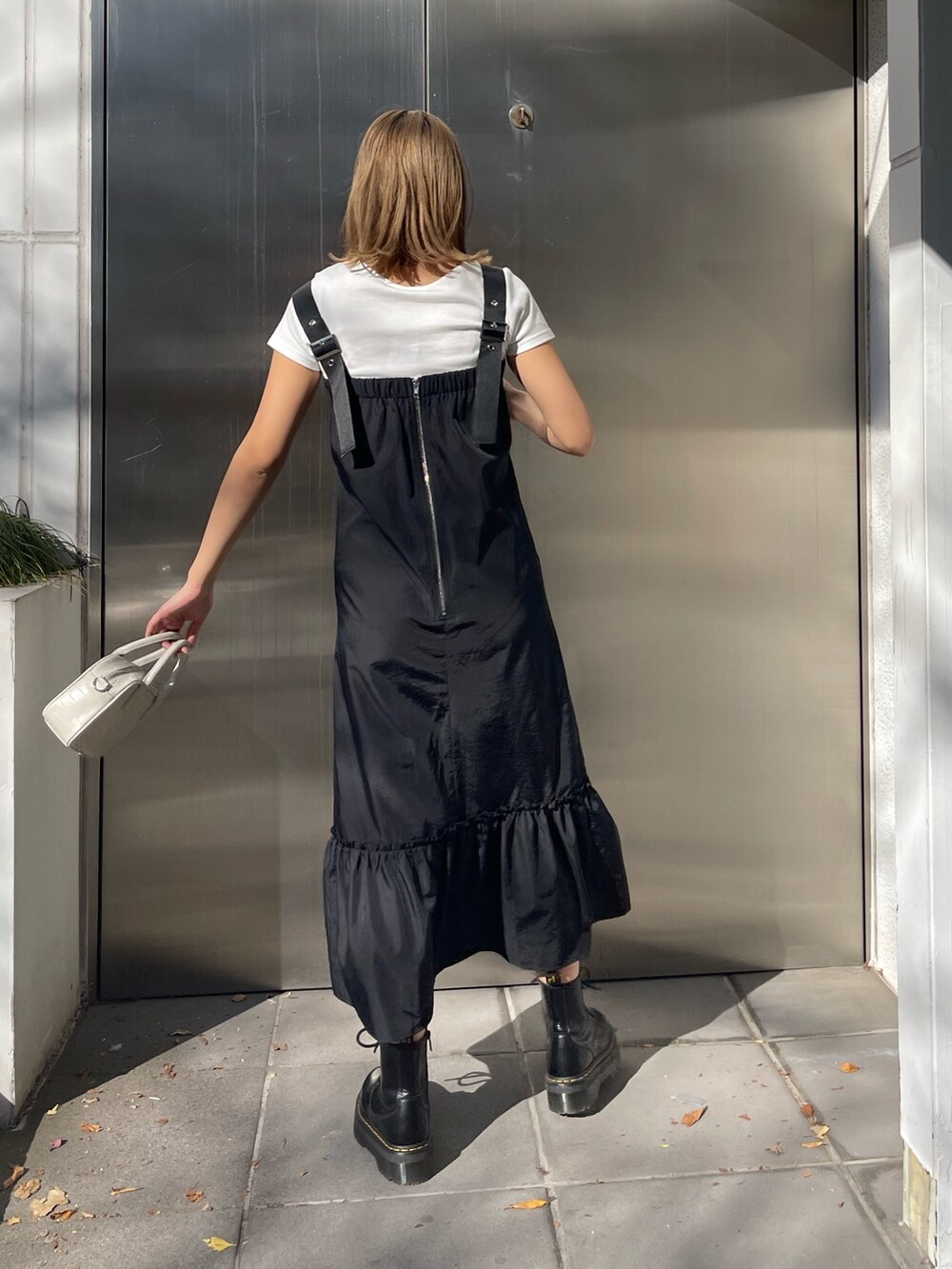 ブラック系のワンピース、ホワイト系のショルダーバッグ、ブラック系のブーツを着用したレディースの冬コーディネートの2枚目の写真