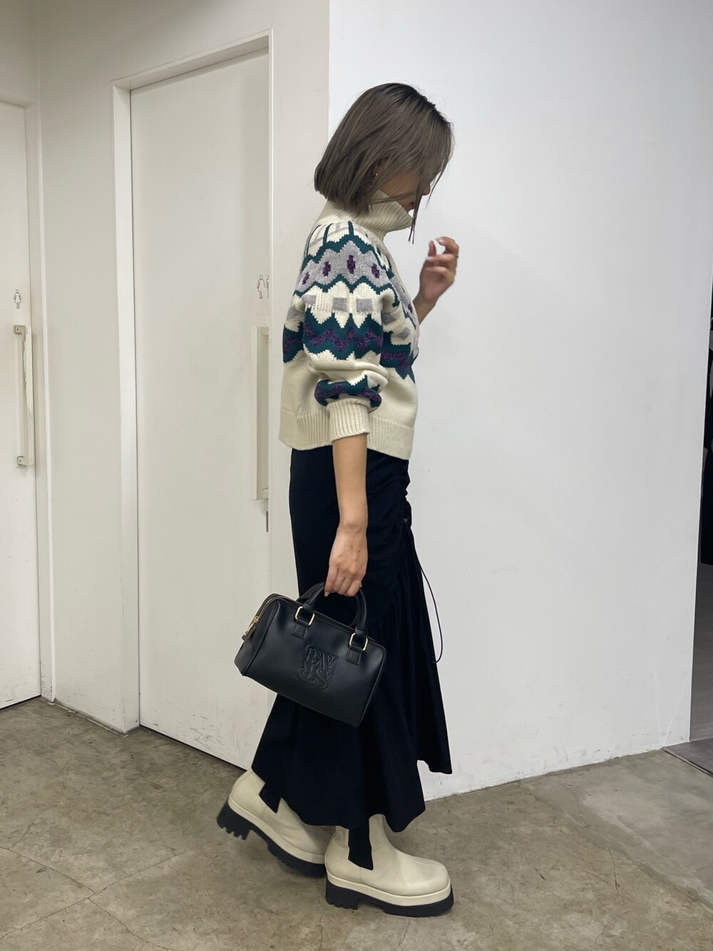 ブラック系のスカート、ホワイト系のブーツ、ホワイト系のニット/セーターを着用したレディースの秋コーディネートの4枚目の写真