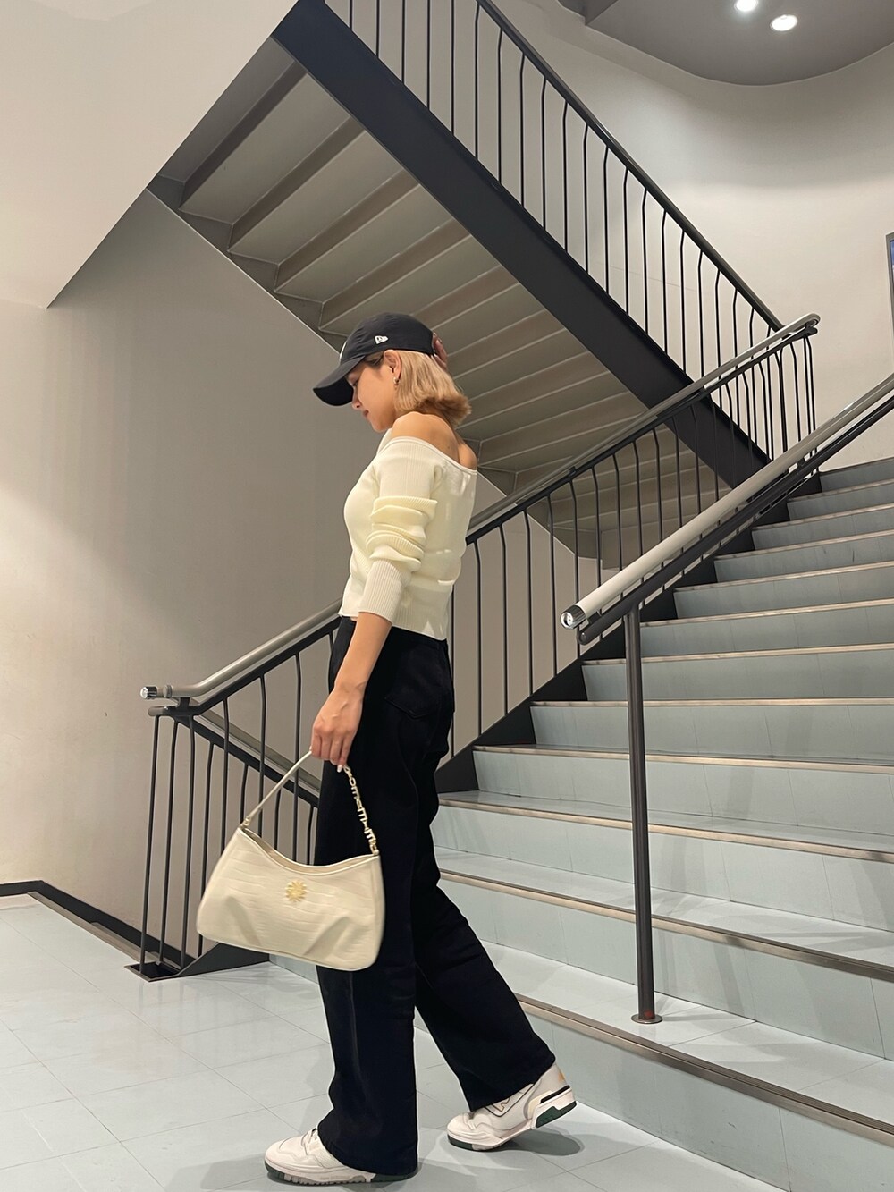 ホワイト系のニット/セーター、ブラック系のデニムパンツ、ホワイト系のハンドバッグを着用したレディースの夏コーディネートの5枚目の写真