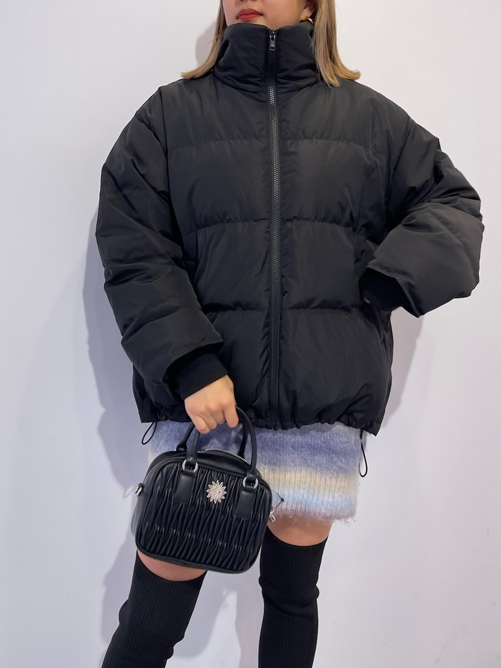 パープル系のニット/セーター、ブラック系のブーツ、ブラック系のダウンジャケット/コートを着用したレディースの冬コーディネートの6枚目の写真