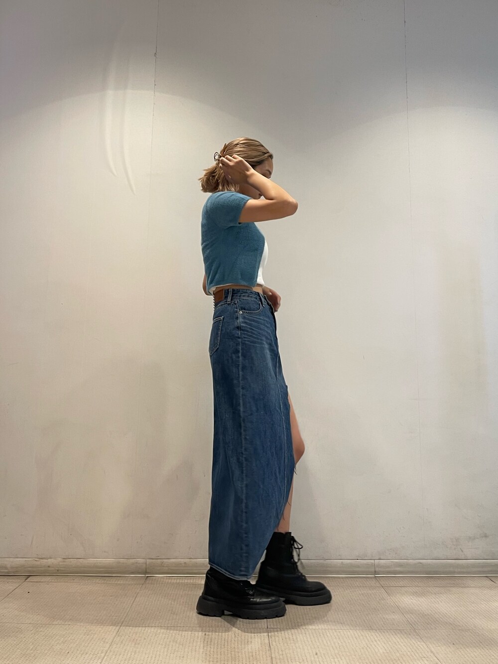 ブルー系のニット/セーター、ホワイト系のキャミソール、ブルー系のデニムスカートを着用したレディースの夏コーディネートの3枚目の写真