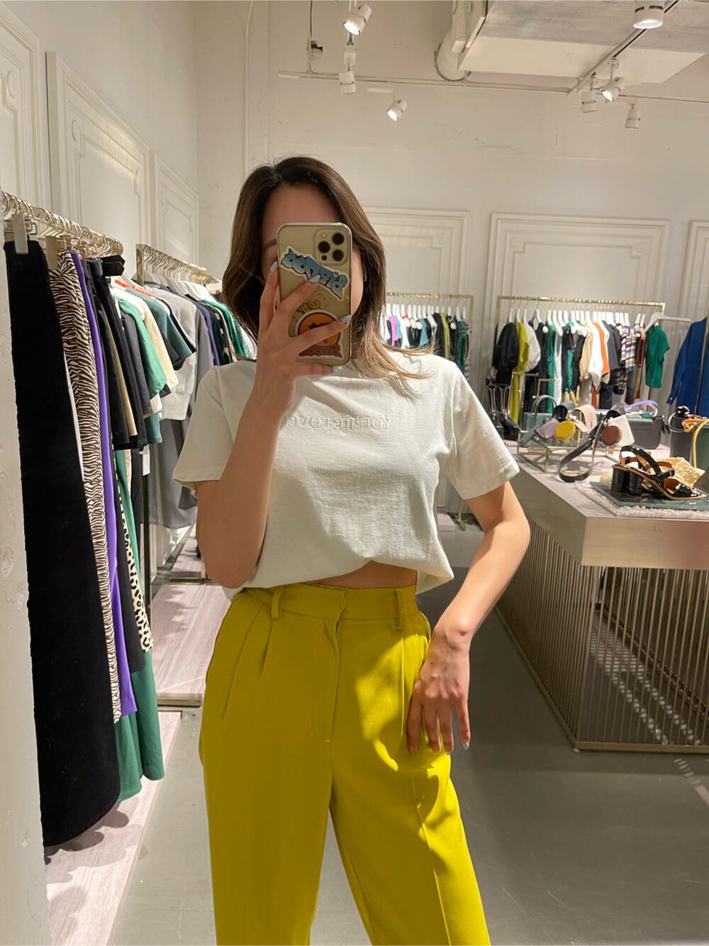 イエロー系のスラックス、ホワイト系のTシャツ/カットソー、ホワイト系のサンダルを着用したレディースの春コーディネートの2枚目の写真