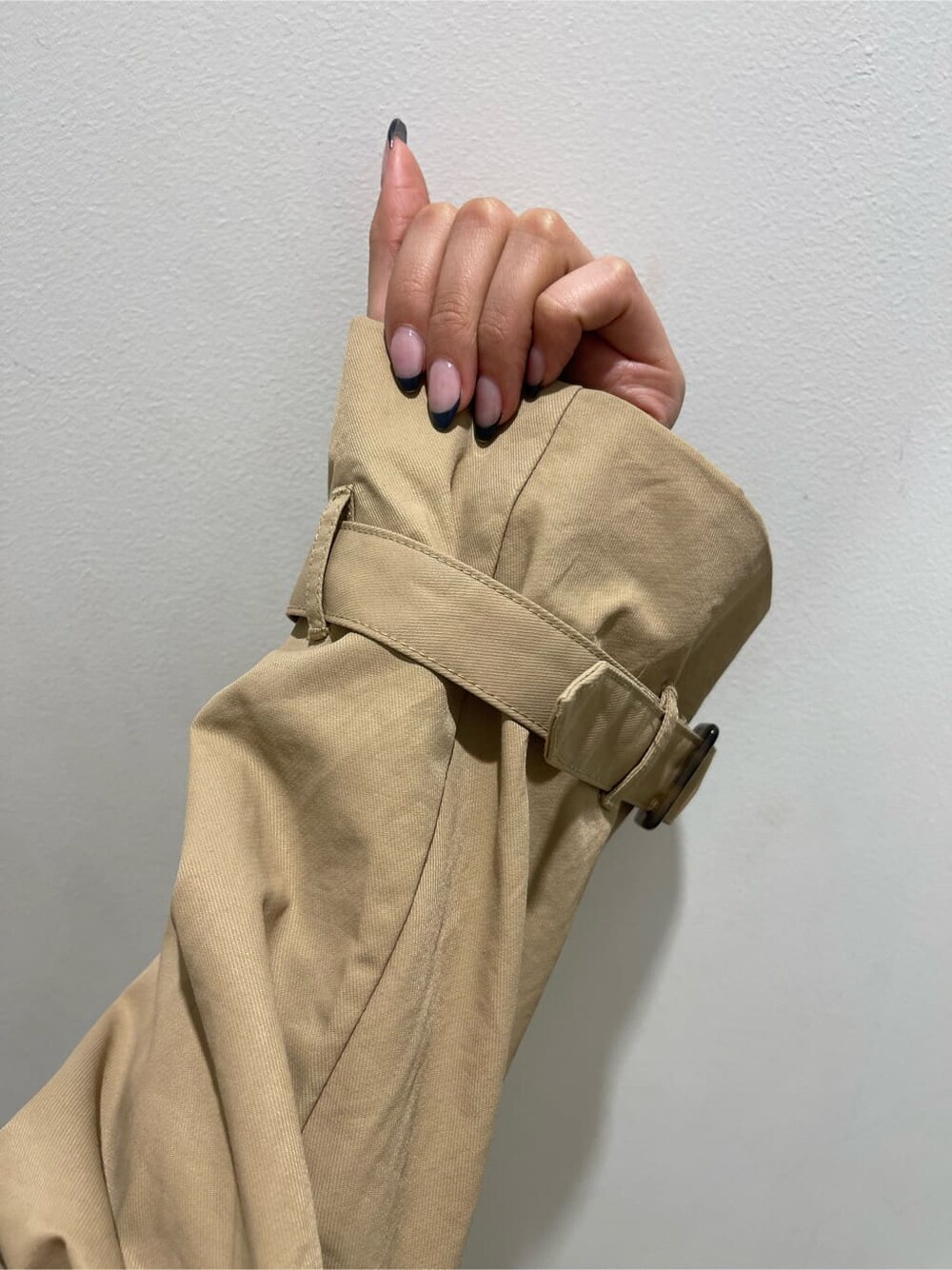 ブラック系のパンプス、ベージュ系のトレンチコート、ブルー系のデニムパンツを着用したレディースの冬コーディネートの4枚目の写真