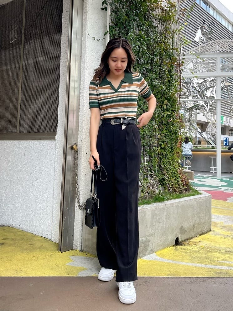 ブラック系のショルダーバッグ、グリーン系のニット/セーター、ブラック系のスラックスを着用したレディースの春コーディネートの2枚目の写真