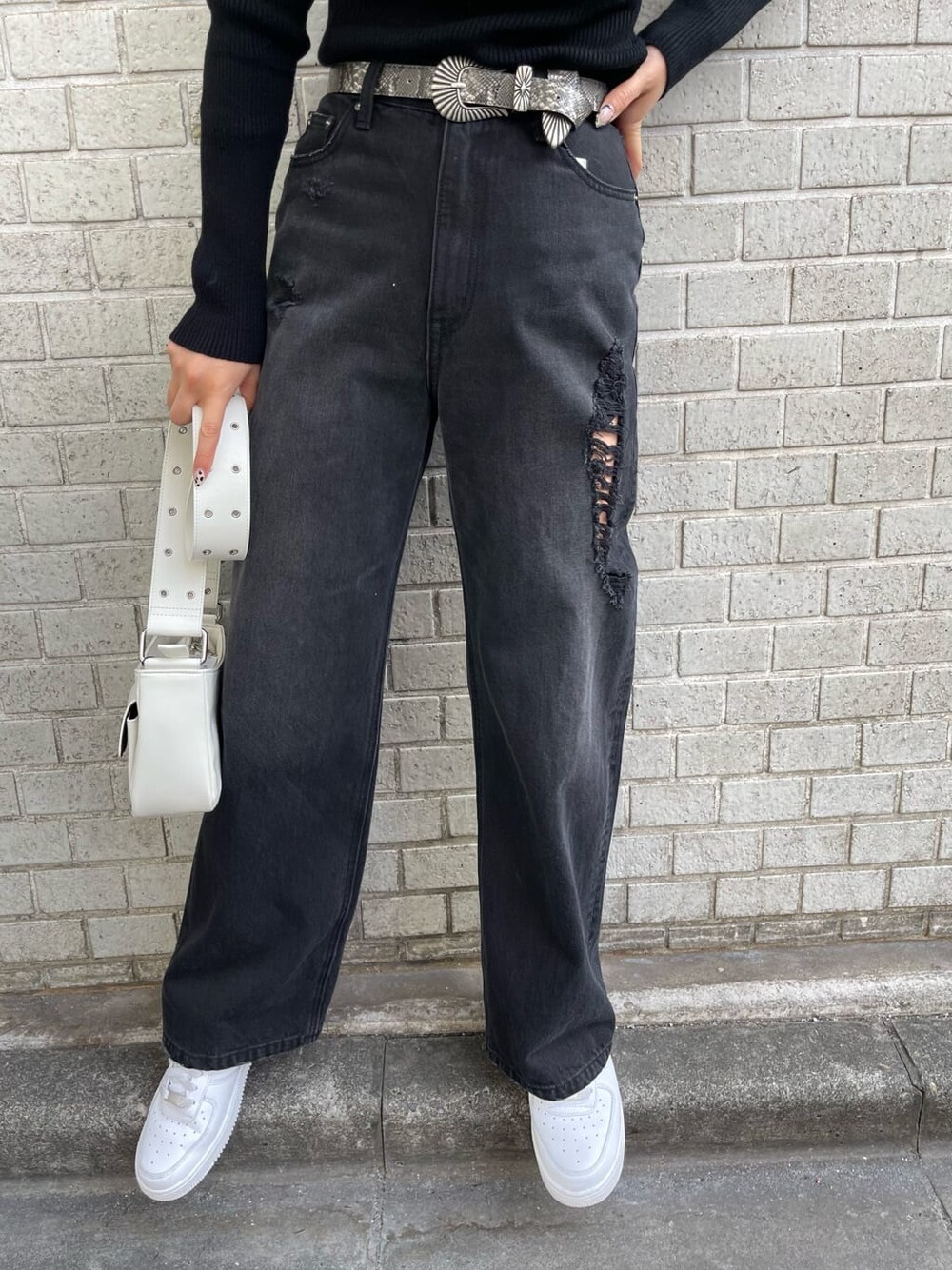 ブラック系のデニムパンツ、ブラック系のニット/セーター、ホワイト系のショルダーバッグを着用したレディースの冬コーディネートの5枚目の写真